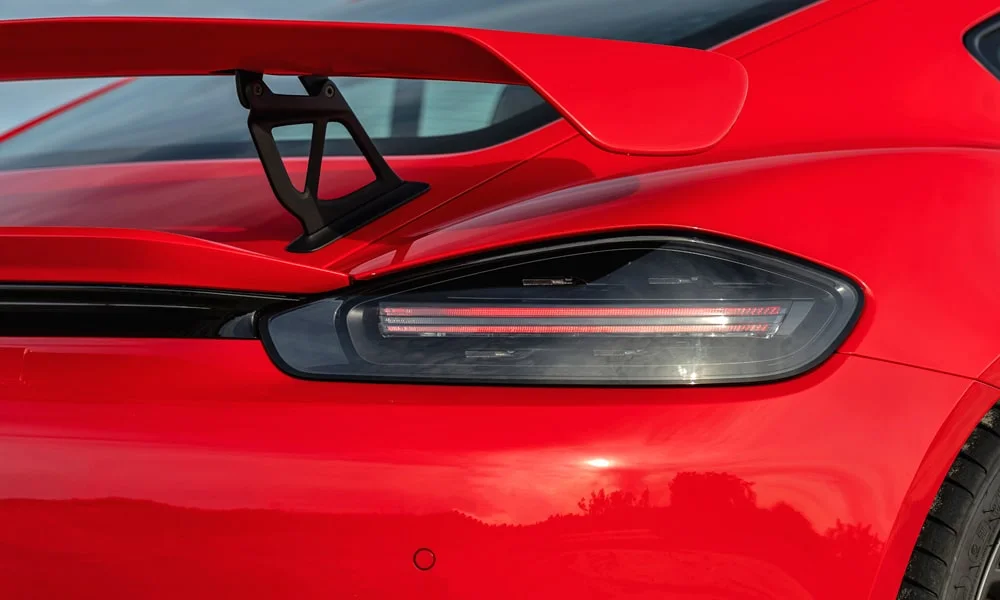 Фото Porsche 718 Cayman GT4 — задние фонари. Рассеиватель фонаря вблизи: компоновка секций габарита, стопа и поворотника. Динамические поворотники с бегущей индикацией встречаются в старших комплектациях Porsche 718 Cayman GT4 — задние фонари
