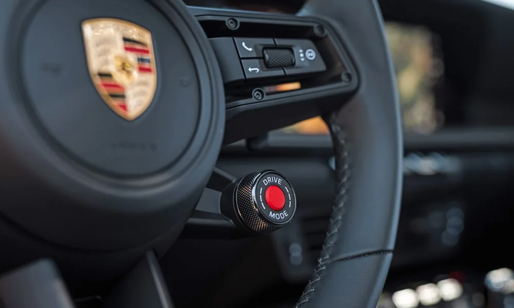 Фото Porsche 911 — руль, фото 3. Обшивка обода и компоновка спиц крупным планом. Клавиши на спицах управляют медиа, круизом и ассистентами — руки остаются на руле Porsche 911 — руль, фото 3