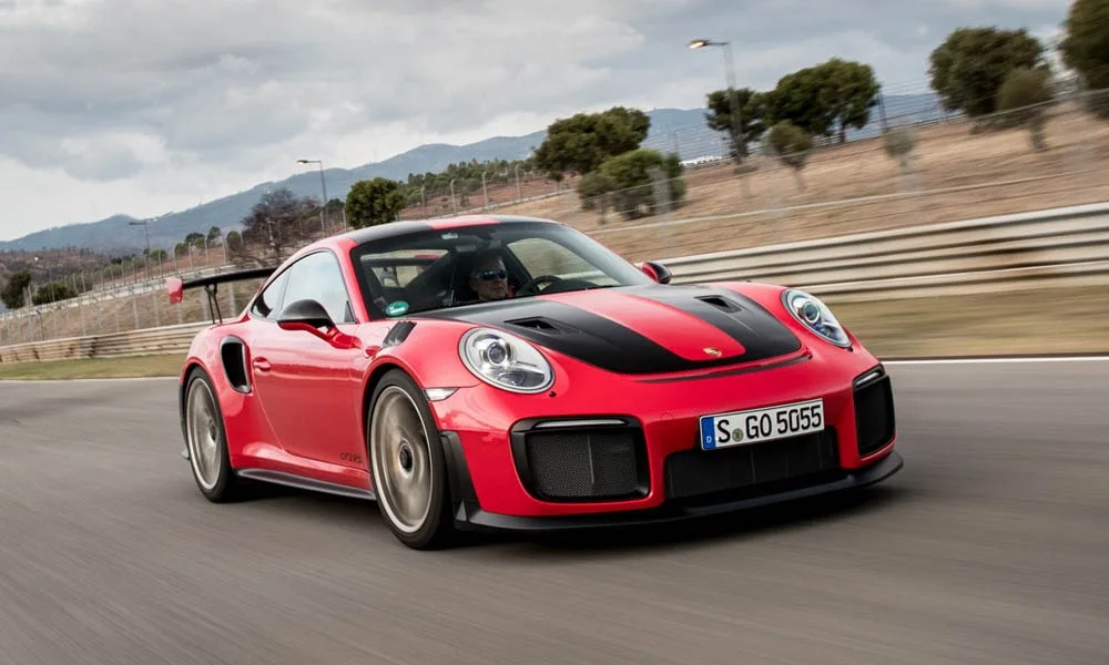 Фото Porsche 911 GT2 RS — вид спереди, фото 7. Передок в красном исполнении — крупная светотехника и выразительный бампер. Рисунок ходовых огней — подпись модели, по нему её узнают в потоке Porsche 911 GT2 RS — вид спереди, фото 7