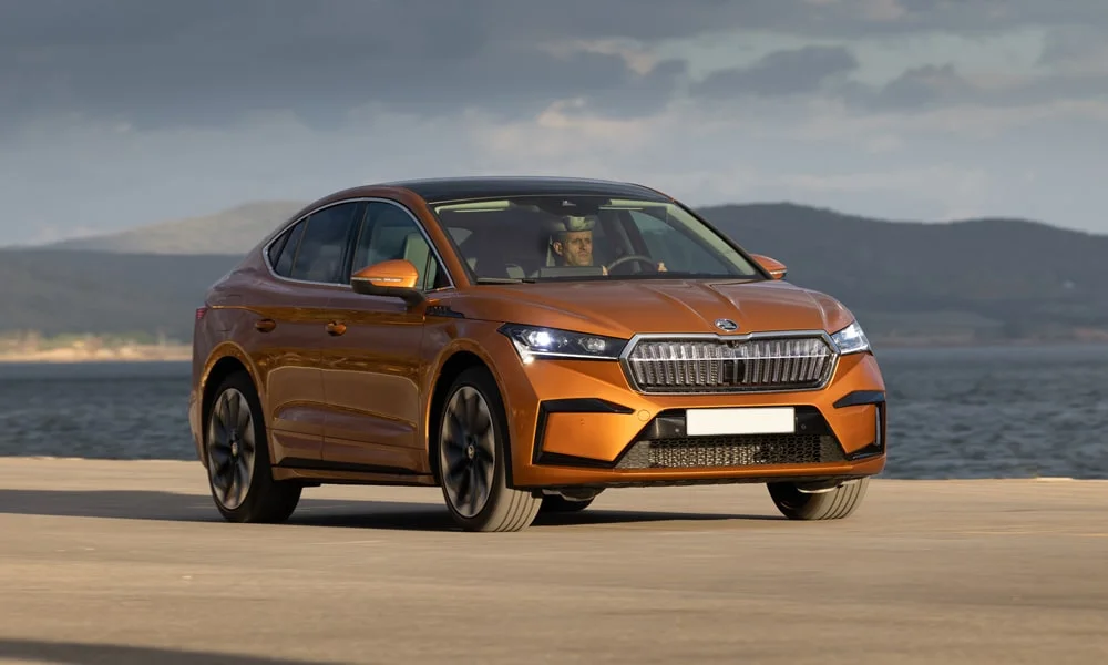 Фото Skoda Enyaq Coupe (2024) — вид спереди, фото 4. Кузов в оранжевом цвете: рисунок оптики и решётки задаёт узнаваемое «лицо» модели Skoda Enyaq Coupe (2024) — вид спереди, фото 4
