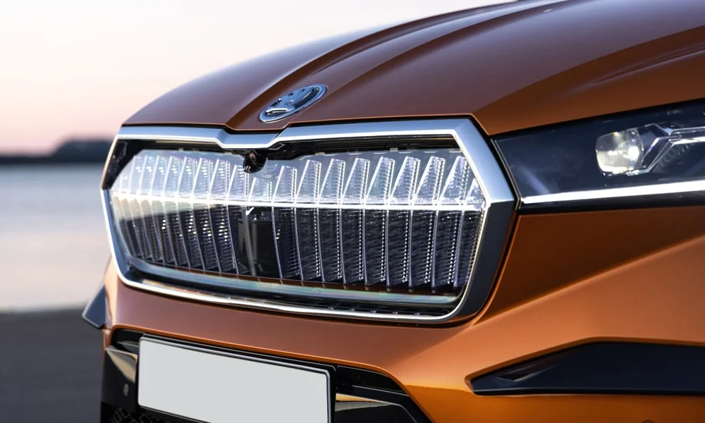 Фото Skoda Enyaq Coupe (2024) — решётка радиатора. Фирменный рисунок облицовки — визитная карточка марки. За решёткой у многих комплектаций стоит радар адаптивного круиз-контроля Skoda Enyaq Coupe (2024) — решётка радиатора