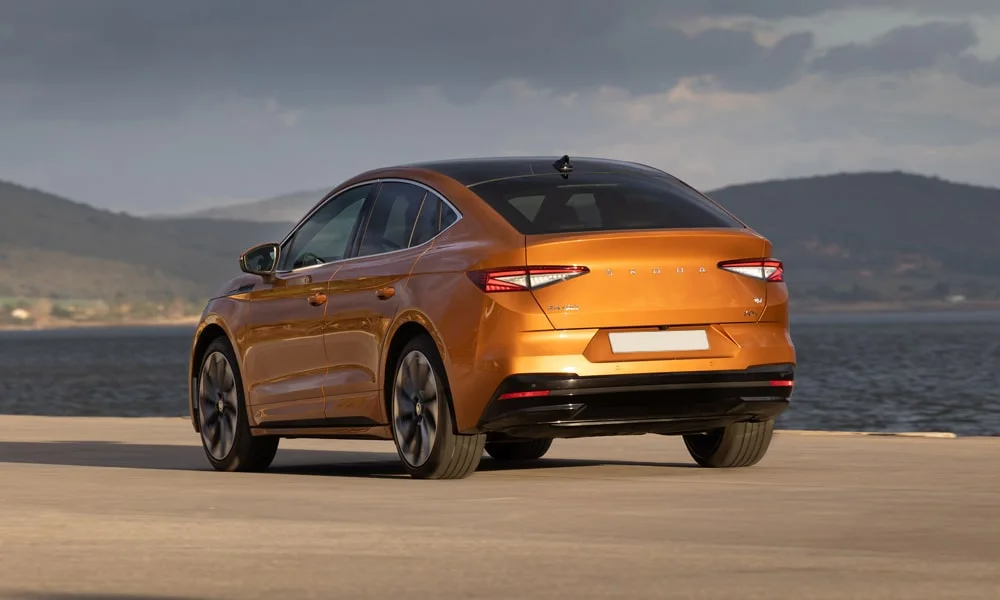 Фото Skoda Enyaq Coupe (2024) — вид сзади, фото 4. Оранжевый кузов сзади — фонари и бампер определяют ночной образ модели. Насадки выхлопа или их имитация внизу бампера различают версии Skoda Enyaq Coupe (2024) — вид сзади, фото 4