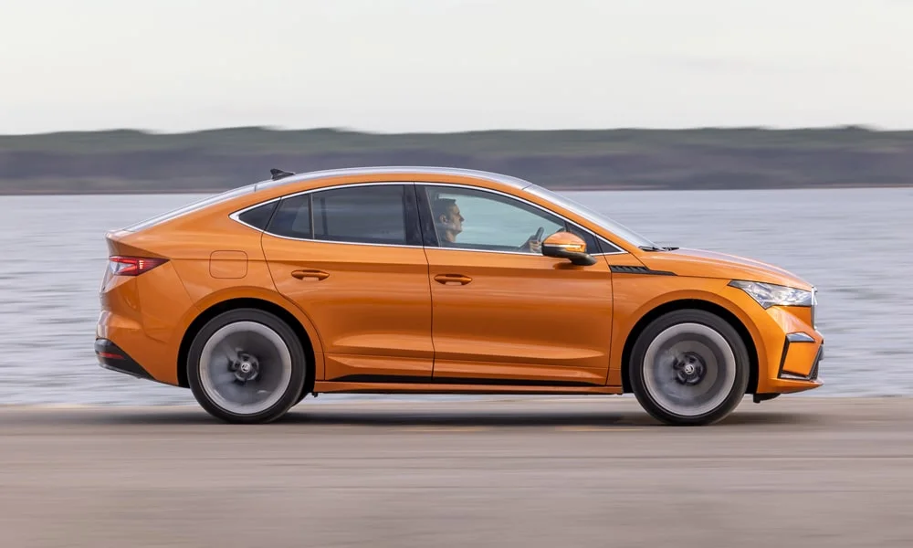 Фото Skoda Enyaq Coupe (2024) — вид сбоку, фото 6. Профиль в оранжевом цвете: соотношение колёсной базы и свесов Skoda Enyaq Coupe (2024) — вид сбоку, фото 6