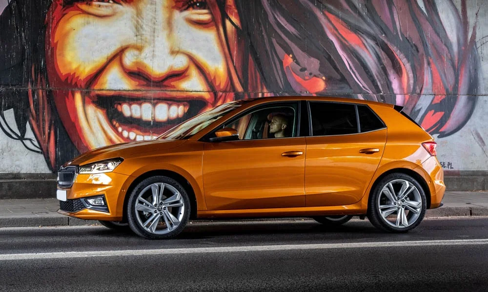 Фото Skoda Fabia — вид сбоку. Сбоку читаются линия остекления и характер выштамповок на оранжевом кузове Skoda Fabia — вид сбоку