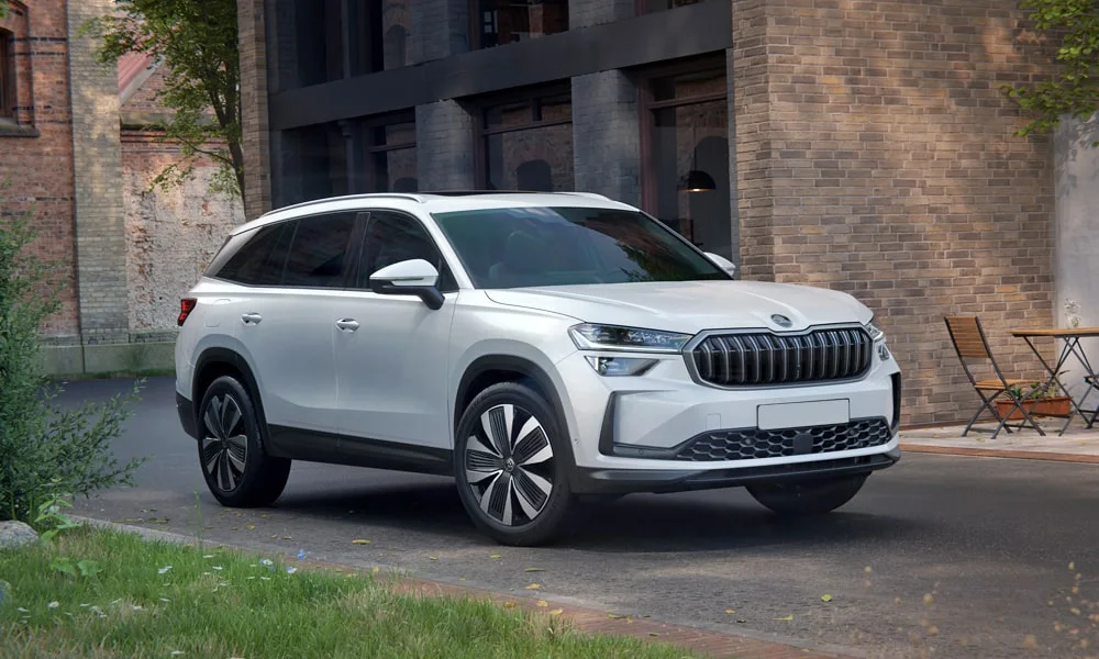 Фото Skoda Kodiaq (2024) — вид спереди, фото 5. Белый кузов, строгая симметрия оптики — базовый ракурс знакомства с дизайном. Рисунок ходовых огней — подпись модели, по нему её узнают в потоке Skoda Kodiaq (2024) — вид спереди, фото 5