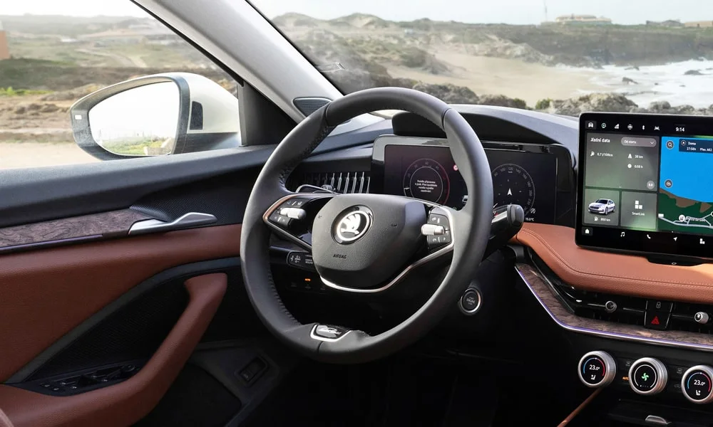 Фото Skoda Superb Combi (2024) — передняя панель. Панель в коричневой отделке — видна компоновка экранов и органов управления. Мягкие материалы верхнего яруса и вставки задают уровень интерьера Skoda Superb Combi (2024) — передняя панель