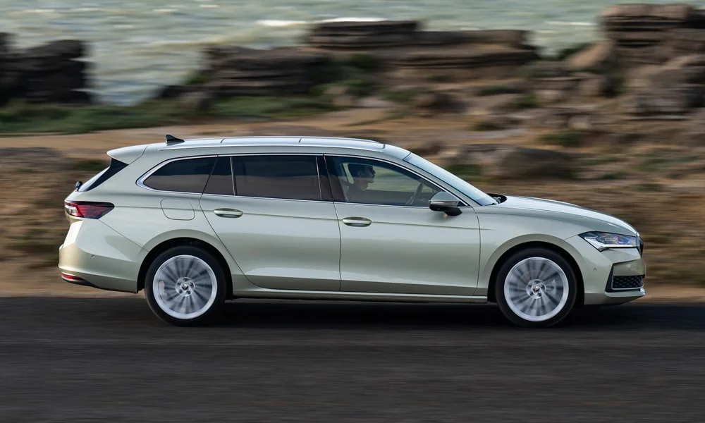 Фото Skoda Superb Combi (2024) — вид сбоку, фото 4. Сбоку читаются линия остекления и характер выштамповок на белом кузове. Хромированные или чёрные молдинги окон отличают комплектации Skoda Superb Combi (2024) — вид сбоку, фото 4