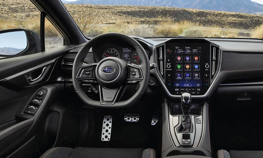 Фото Subaru WRX STI (2024) — передняя панель. Передняя панель в тёмной отделке: расположение экранов и дефлекторов. Мягкие материалы верхнего яруса и вставки задают уровень интерьера Subaru WRX STI (2024) — передняя панель