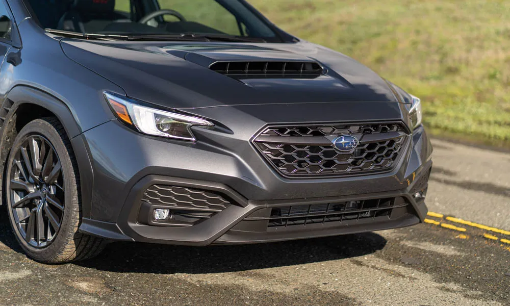 Фото Subaru WRX STI (2024) — вид спереди, фото 4. Серый кузов, строгая симметрия оптики — базовый ракурс знакомства с дизайном. Дневные ходовые огни включаются автоматически с запуском Subaru WRX STI (2024) — вид спереди, фото 4