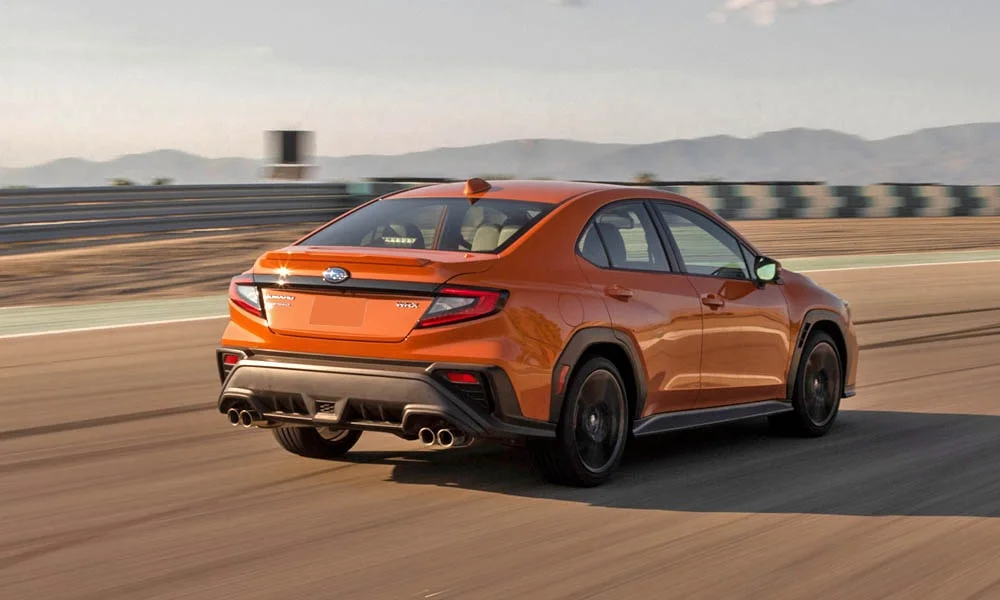 Фото Subaru WRX STI (2024) — вид сзади, фото 9. Линия крыши, стойки и задняя дверь в оранжевом исполнении. Насадки выхлопа или их имитация внизу бампера различают версии Subaru WRX STI (2024) — вид сзади, фото 9