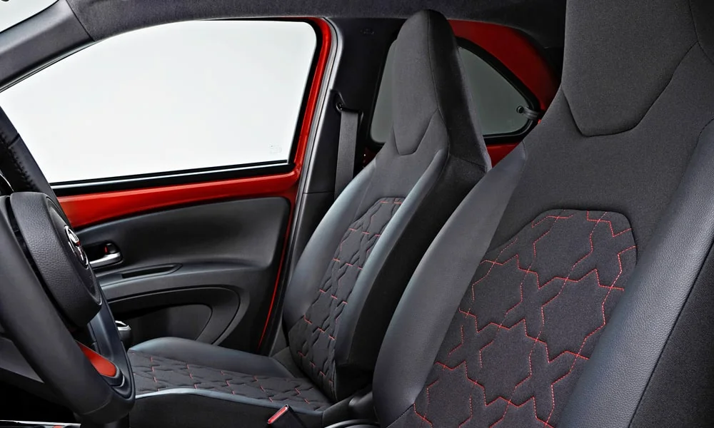 Фото Toyota Aygo X — передние сиденья. Профиль кресел: боковая поддержка и подголовники. Выраженная боковая поддержка держит в поворотах Toyota Aygo X — передние сиденья
