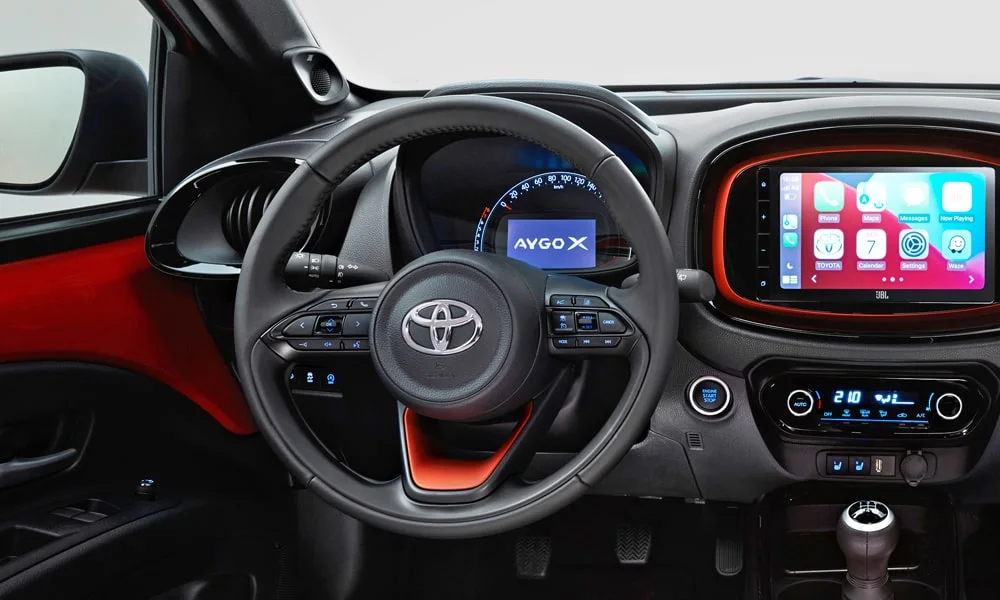 Фото Toyota Aygo X — интерьер. Общий план салона: архитектура панели, консоль и кресла. Светлая гамма зрительно расширяет салон, тёмная — практичнее в уходе Toyota Aygo X — интерьер