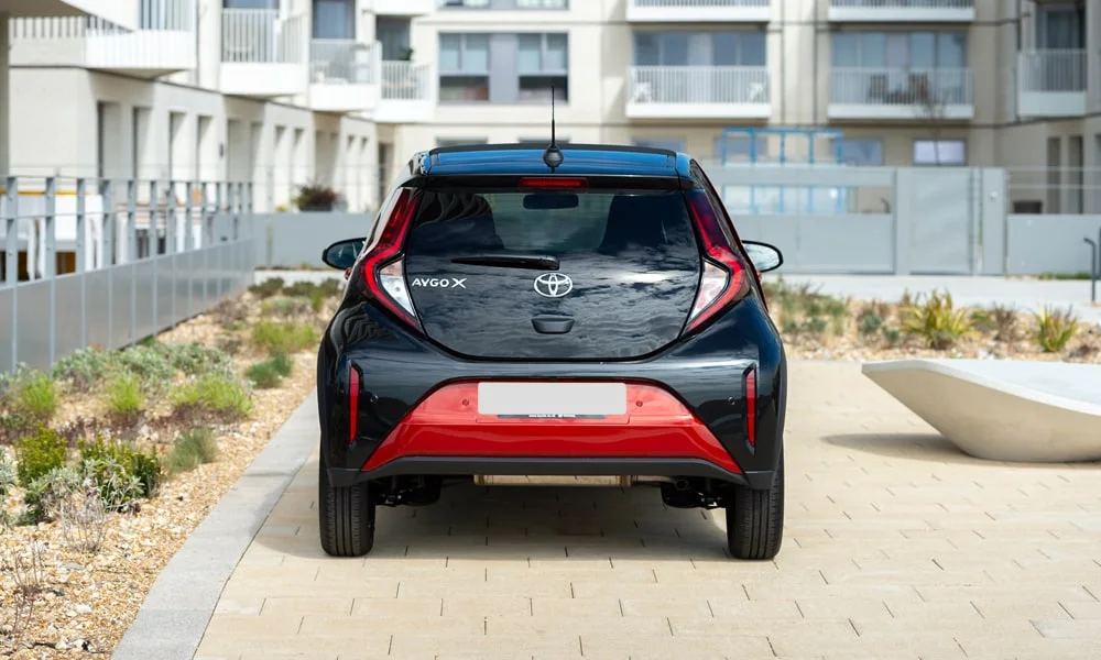 Фото Toyota Aygo X — вид сзади, фото 5. Линия крыши, стойки и задняя дверь в чёрном исполнении. Насадки выхлопа или их имитация внизу бампера различают версии Toyota Aygo X — вид сзади, фото 5
