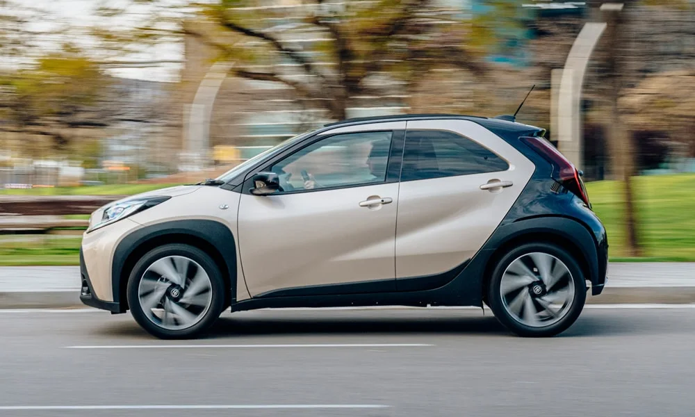 Фото Toyota Aygo X — вид сбоку, фото 2. Профиль в бежевом цвете: соотношение колёсной базы и свесов. Длинная база — простор второго ряда; короткие свесы упрощают парковку Toyota Aygo X — вид сбоку, фото 2