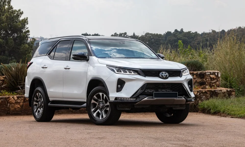 Фото Toyota Fortuner (2024) — вид спереди, фото 6. Кузов в белом цвете: рисунок оптики и решётки задаёт узнаваемое «лицо» модели. Дневные ходовые огни включаются автоматически с запуском Toyota Fortuner (2024) — вид спереди, фото 6