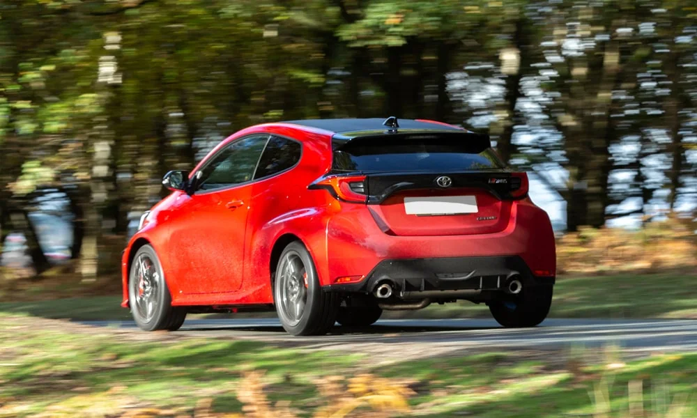 Фото Toyota GR Yaris — вид сзади, фото 3. Красный кузов сзади — фонари и бампер определяют ночной образ модели. Насадки выхлопа или их имитация внизу бампера различают версии Toyota GR Yaris — вид сзади, фото 3
