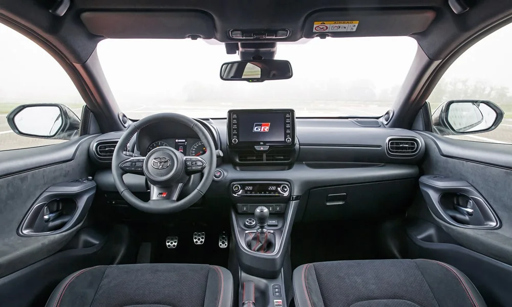 Фото Toyota GR Yaris — руль, фото 2. Обшивка обода и компоновка спиц крупным планом. Клавиши на спицах управляют медиа, круизом и ассистентами — руки остаются на руле Toyota GR Yaris — руль, фото 2