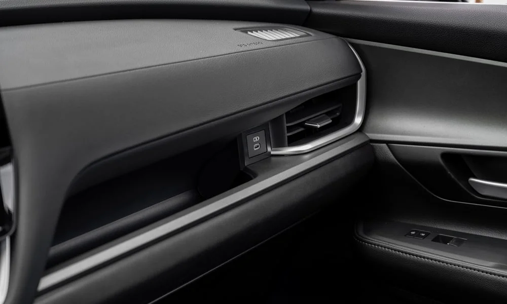 Фото Toyota Grand Highlander (2024) — дверная карта. Внутренняя панель двери: сочетание материалов и компоновка управления в тёмной гамме. Решётка динамика в двери — часть штатной акустики Toyota Grand Highlander (2024) — дверная карта