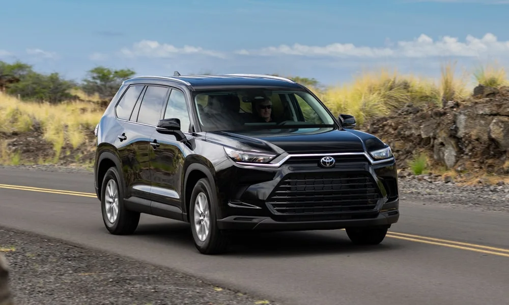 Фото Toyota Grand Highlander (2024) — вид спереди, фото 6. Чёрный кузов, строгая симметрия оптики — базовый ракурс знакомства с дизайном. Дневные ходовые огни включаются автоматически с запуском Toyota Grand Highlander (2024) — вид спереди, фото 6