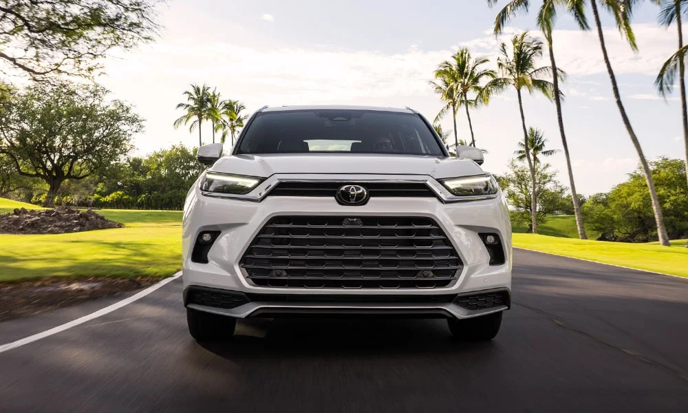 Фото Toyota Grand Highlander (2024) — вид спереди, фото 9. Передок в белом исполнении — крупная светотехника и выразительный бампер. Дневные ходовые огни включаются автоматически с запуском Toyota Grand Highlander (2024) — вид спереди, фото 9