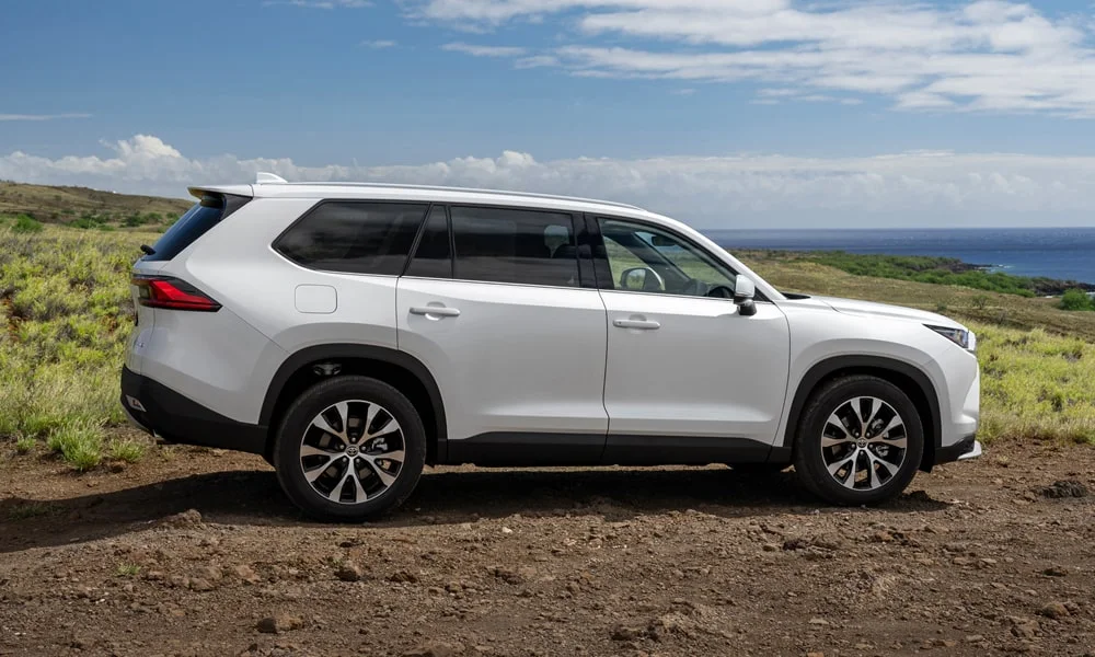 Фото Toyota Grand Highlander (2024) — вид сзади, фото 6. Линия крыши, стойки и задняя дверь в белом исполнении. Насадки выхлопа или их имитация внизу бампера различают версии Toyota Grand Highlander (2024) — вид сзади, фото 6