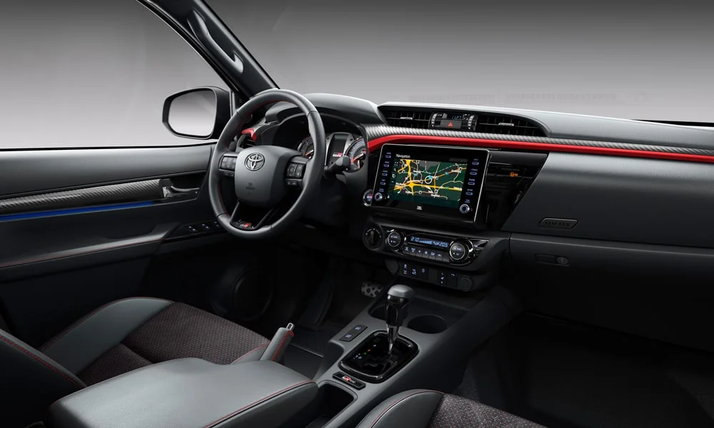 Фото Toyota Hilux (2024) — передняя панель. Архитектура передней панели: ярусы, вставки и консоль в красно-чёрной гамме Toyota Hilux (2024) — передняя панель