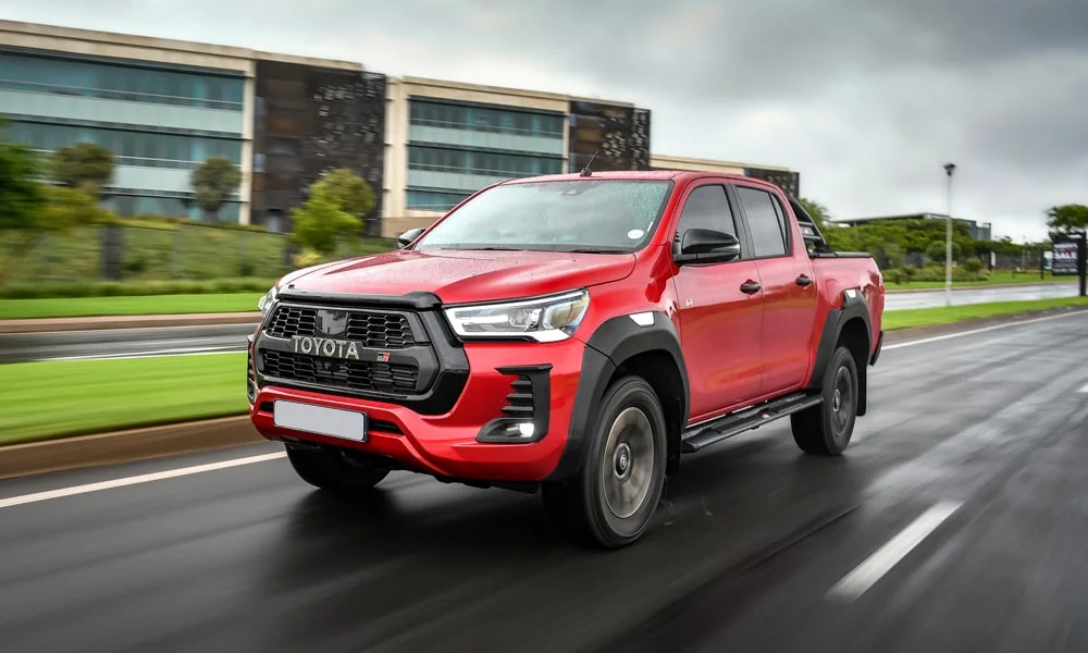 Фото Toyota Hilux (2024) — вид спереди, фото 6. Передок в красном исполнении — крупная светотехника и выразительный бампер. Рисунок ходовых огней — подпись модели, по нему её узнают в потоке Toyota Hilux (2024) — вид спереди, фото 6