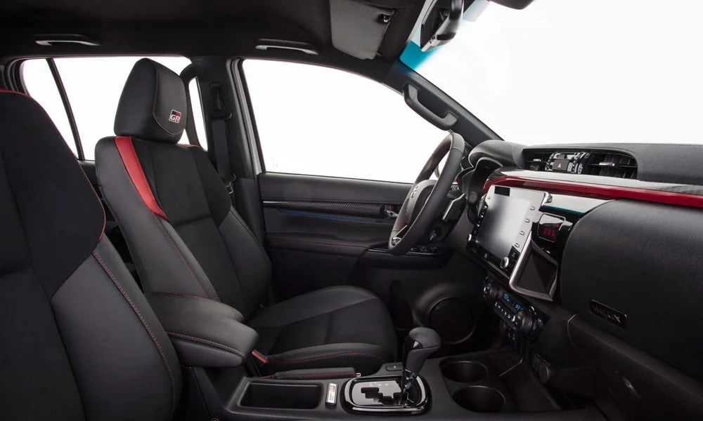 Фото Toyota Hilux (2024) — интерьер. Общий план салона: архитектура панели, консоль и кресла. Светлая гамма зрительно расширяет салон, тёмная — практичнее в уходе Toyota Hilux (2024) — интерьер