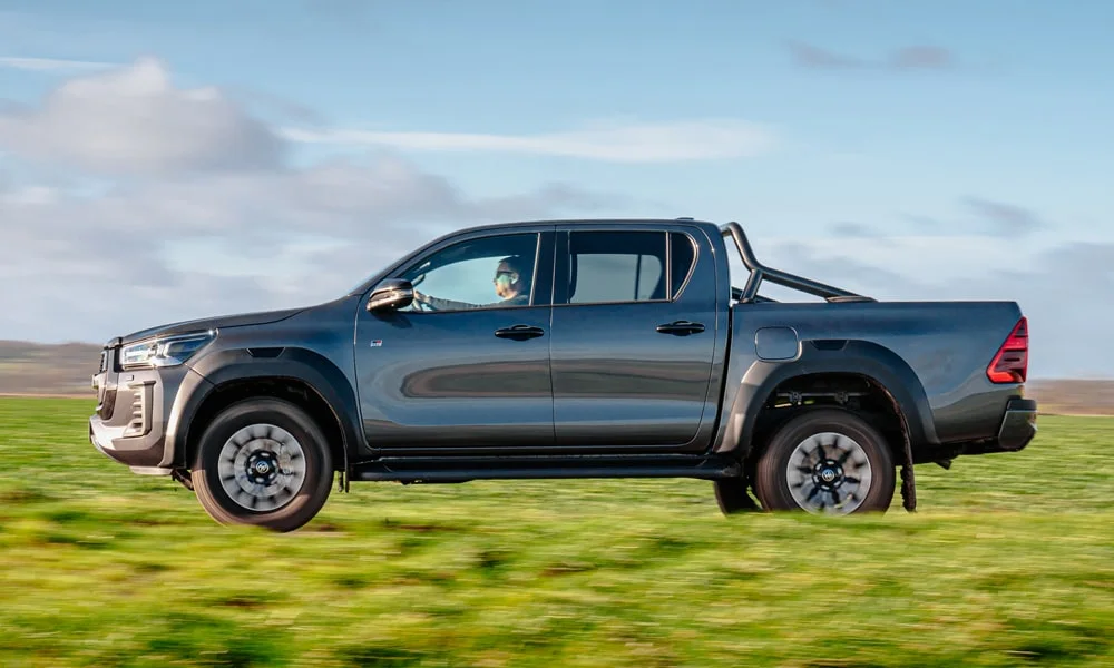 Фото Toyota Hilux (2024) — вид сбоку, фото 2. Профиль кузова: колёсная база, свесы и линия остекления. Хромированные или чёрные молдинги окон отличают комплектации Toyota Hilux (2024) — вид сбоку, фото 2