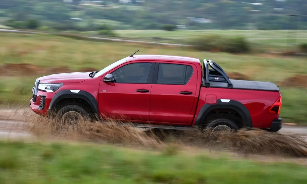 Фото Toyota Hilux (2024) — вид сбоку, фото 4. Профиль кузова: колёсная база, свесы и линия остекления. Хромированные или чёрные молдинги окон отличают комплектации Toyota Hilux (2024) — вид сбоку, фото 4