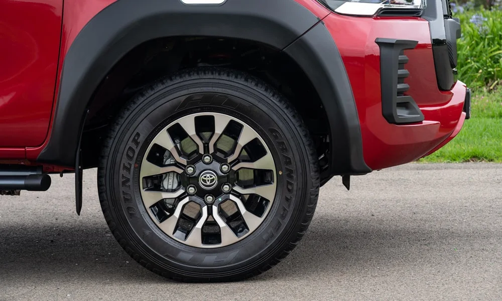 Фото Toyota Hilux (2024) — колесо и диск. Пятилучевой диск — классика, лёгкая в мойке и визуально стройная. Рекомендованные размеры шин и давление — на табличке в проёме водительской двери Toyota Hilux (2024) — колесо и диск