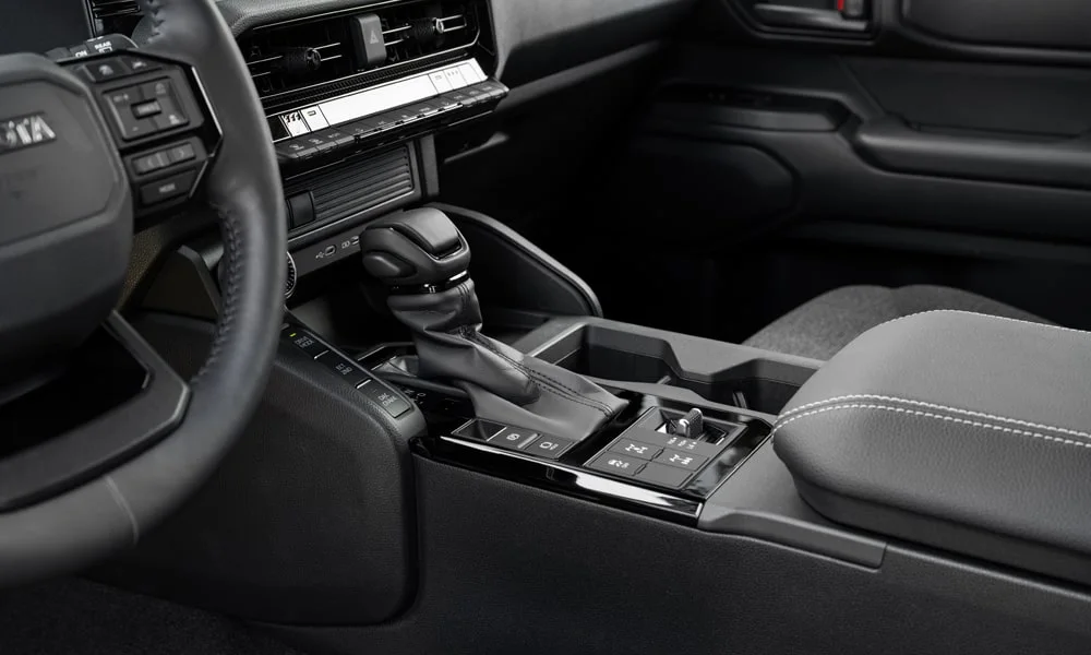 Фото Toyota Land Cruiser Prado (2024) — селектор коробки передач. Управление коробкой: компактный селектор освобождает место на тоннеле. Режимы движения и электронный ручник собраны рядом с селектором Toyota Land Cruiser Prado (2024) — селектор коробки передач