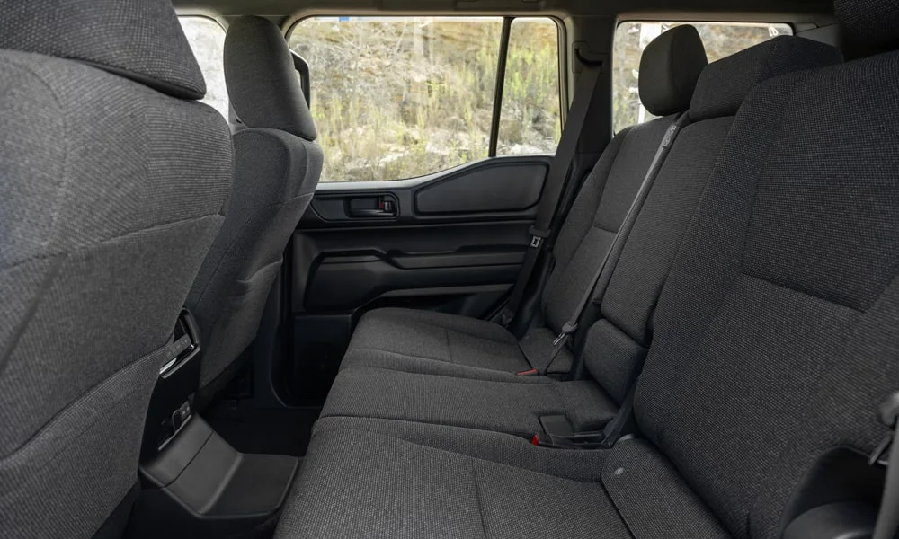 Фото Toyota Land Cruiser Prado (2024) — задние сиденья. Задний диван в практичной ткани: посадка и центральный подлокотник. Крепления ISOFIX для детских кресел — в основании спинки Toyota Land Cruiser Prado (2024) — задние сиденья