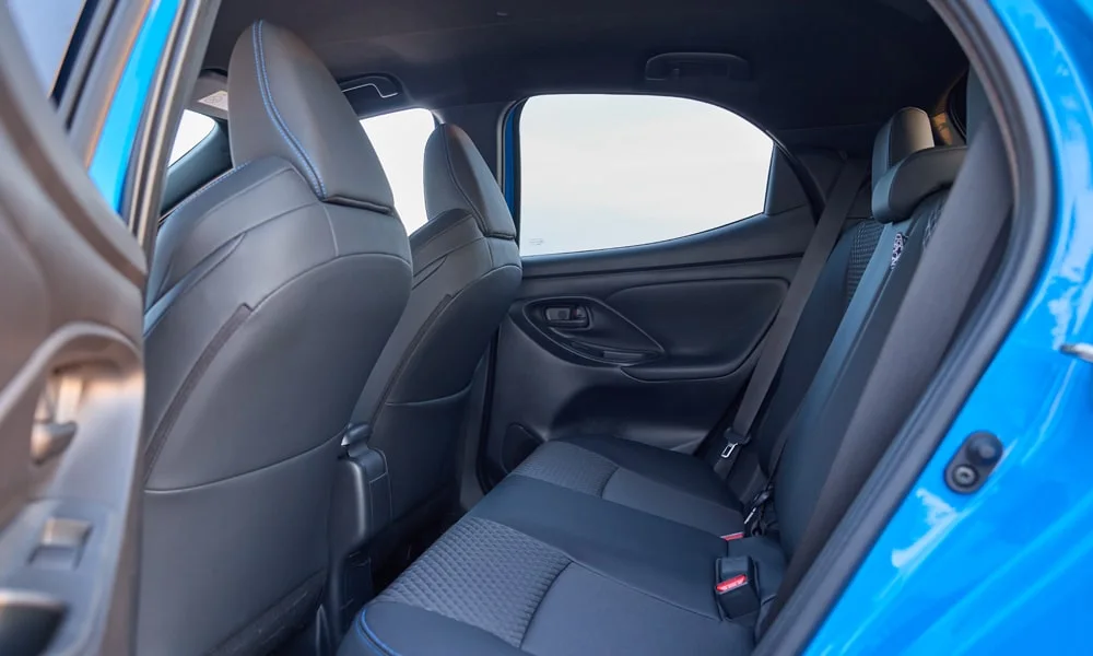 Фото Toyota Yaris — задние сиденья. Посадка второго ряда: подголовники и подлокотник. Плоский пол упрощает посадку втроём Toyota Yaris — задние сиденья