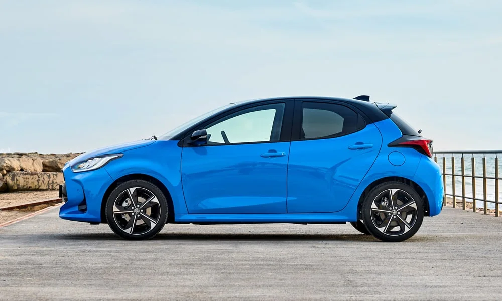 Фото Toyota Yaris — вид сбоку, фото 4. Профиль в синем цвете: соотношение колёсной базы и свесов. Длинная база — простор второго ряда; короткие свесы упрощают парковку Toyota Yaris — вид сбоку, фото 4