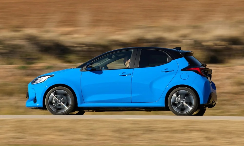Фото Toyota Yaris — вид сбоку, фото 5. Сбоку читаются линия остекления и характер выштамповок на синем кузове Toyota Yaris — вид сбоку, фото 5