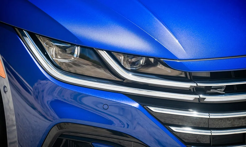 Фото Volkswagen Arteon (2024) — вид спереди, фото 6. Кузов в синем цвете: рисунок оптики и решётки задаёт узнаваемое «лицо» модели. Дневные ходовые огни включаются автоматически с запуском Volkswagen Arteon (2024) — вид спереди, фото 6