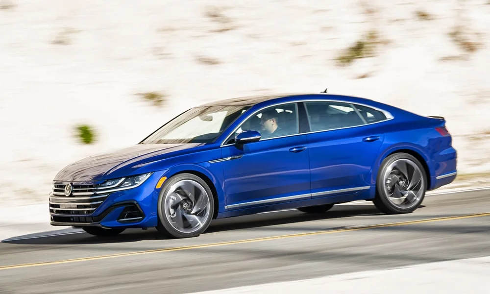 Фото Volkswagen Arteon (2024) — вид спереди, фото 9. Кузов в синем цвете: рисунок оптики и решётки задаёт узнаваемое «лицо» модели. Дневные ходовые огни включаются автоматически с запуском Volkswagen Arteon (2024) — вид спереди, фото 9