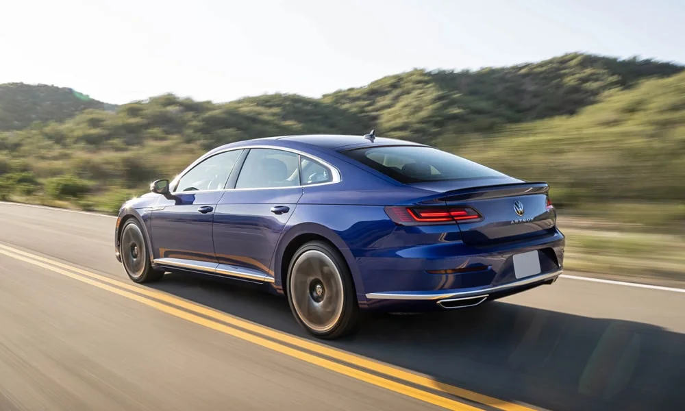 Фото Volkswagen Arteon (2024) — вид сзади, фото 4. Синий кузов сзади — фонари и бампер определяют ночной образ модели. Насадки выхлопа или их имитация внизу бампера различают версии Volkswagen Arteon (2024) — вид сзади, фото 4