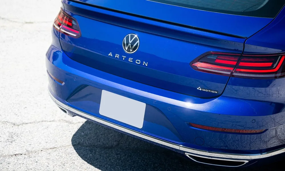Фото Volkswagen Arteon (2024) — вид сзади, фото 9. Корма в синем цвете: графика фонарей и пластика пятой двери. Светодиодная полоса или раздельные секции — задняя оптика стала главным украшением кормы Volkswagen Arteon (2024) — вид сзади, фото 9