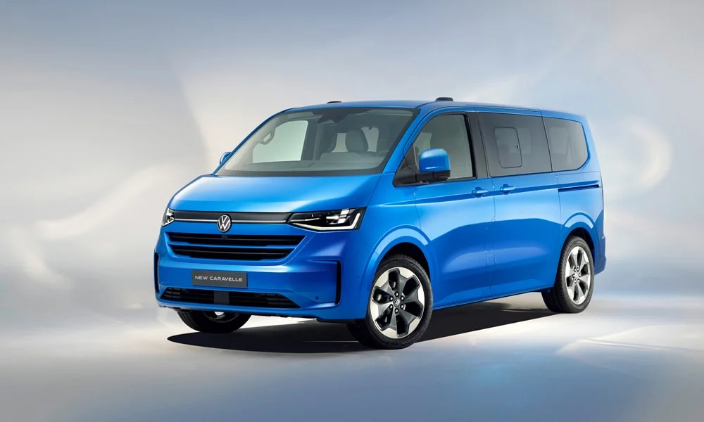 Фото Volkswagen Caravelle (2024) — вид спереди, фото 9. Кузов в синем цвете: рисунок оптики и решётки задаёт узнаваемое «лицо» модели. Дневные ходовые огни включаются автоматически с запуском Volkswagen Caravelle (2024) — вид спереди, фото 9