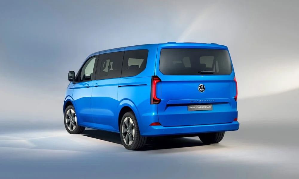 Фото Volkswagen Caravelle (2024) — вид сзади, фото 3. Линия крыши, стойки и задняя дверь в синем исполнении. Светодиодная полоса или раздельные секции — задняя оптика стала главным украшением кормы Volkswagen Caravelle (2024) — вид сзади, фото 3