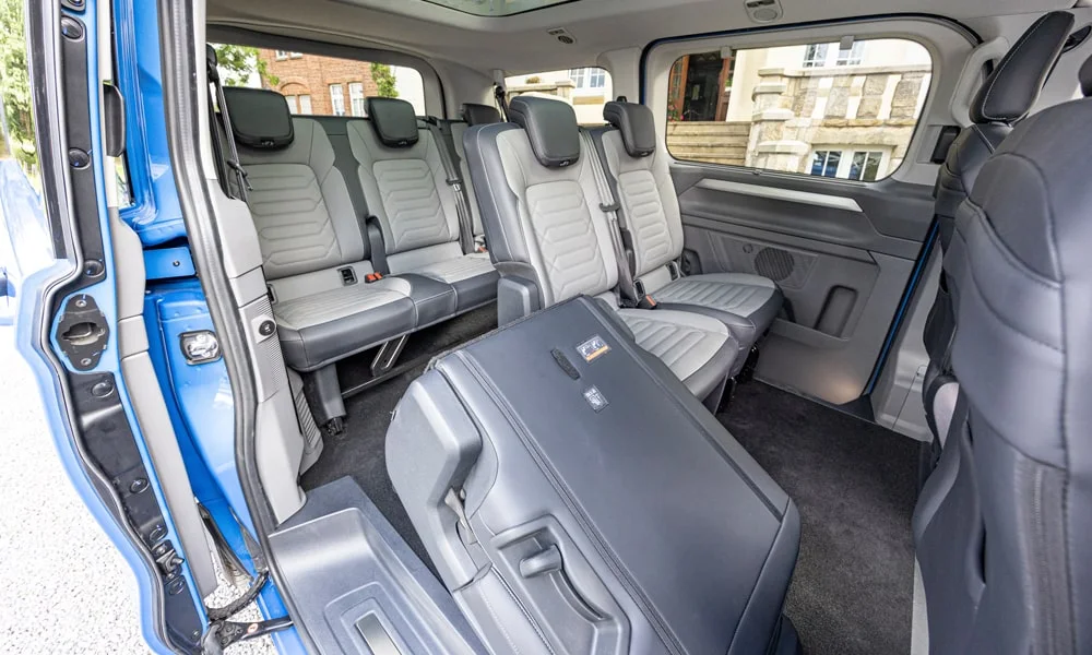 Фото Volkswagen Caravelle (2024) — задние сиденья. Посадка второго ряда: подголовники и подлокотник. Плоский пол упрощает посадку втроём Volkswagen Caravelle (2024) — задние сиденья