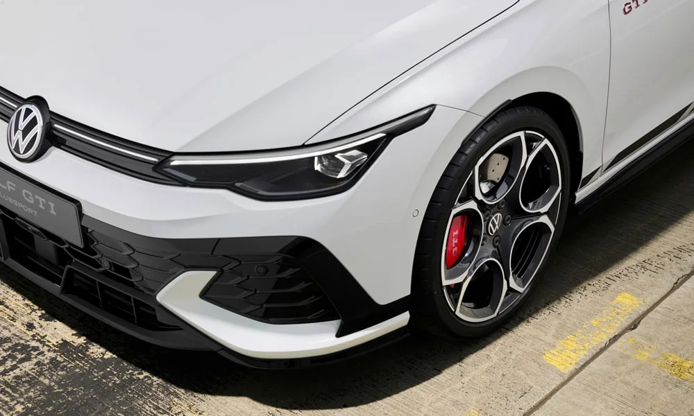 Фото Volkswagen Golf GTI (2024) — вид спереди, фото 4. Белый кузов, строгая симметрия оптики — базовый ракурс знакомства с дизайном Volkswagen Golf GTI (2024) — вид спереди, фото 4