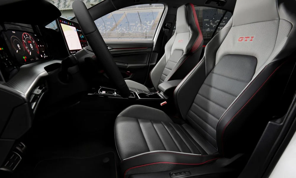 Фото Volkswagen Golf GTI (2024) — интерьер, фото 2. Общий план салона: архитектура панели, консоль и кресла. Светлая гамма зрительно расширяет салон, тёмная — практичнее в уходе Volkswagen Golf GTI (2024) — интерьер, фото 2