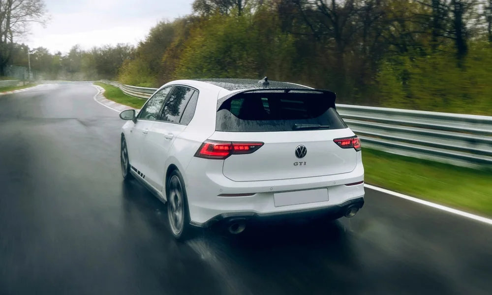 Фото Volkswagen Golf GTI (2024) — вид сзади, фото 8. Белый кузов сзади — фонари и бампер определяют ночной образ модели. Насадки выхлопа или их имитация внизу бампера различают версии Volkswagen Golf GTI (2024) — вид сзади, фото 8