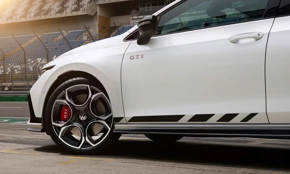 Фото Volkswagen Golf GTI (2024) — вид сбоку, фото 3. Профиль в белом цвете: соотношение колёсной базы и свесов. Хромированные или чёрные молдинги окон отличают комплектации Volkswagen Golf GTI (2024) — вид сбоку, фото 3