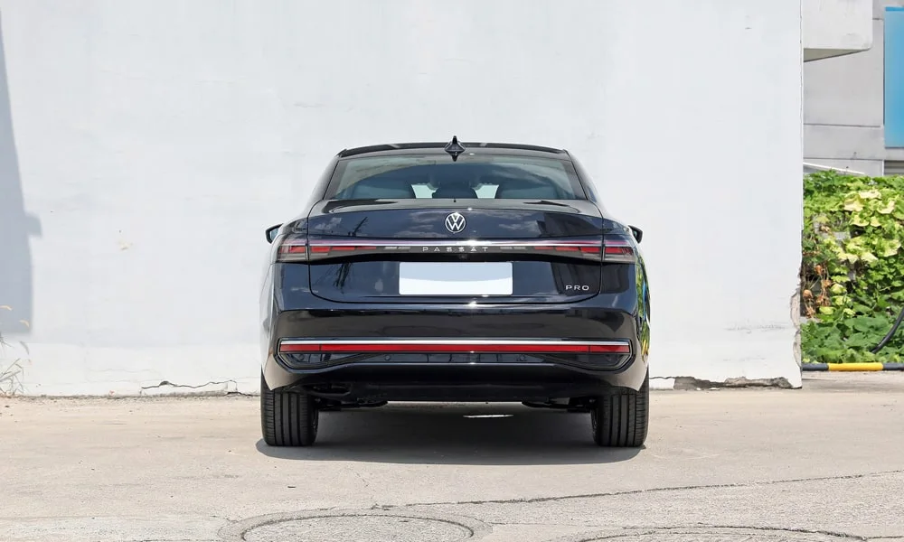Фото Volkswagen Passat (2024) — вид сзади, фото 4. Чёрный кузов сзади — фонари и бампер определяют ночной образ модели. Светодиодная полоса или раздельные секции — задняя оптика стала главным украшением кормы Volkswagen Passat (2024) — вид сзади, фото 4