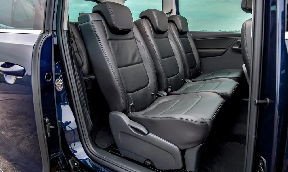 Фото Volkswagen Sharan — задние сиденья. Второй ряд: профиль дивана, подголовники и обивка из гладкой коже. Спинки складываются под длинные грузы у большинства версий Volkswagen Sharan — задние сиденья