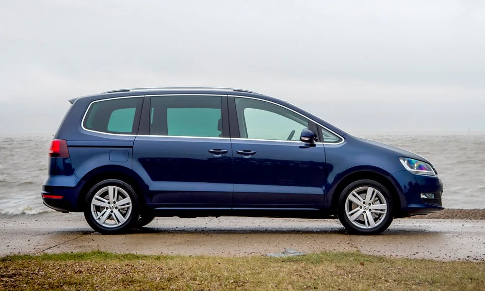 Фото Volkswagen Sharan — вид сбоку, фото 4. Сбоку читаются линия остекления и характер выштамповок на синем кузове. Длинная база — простор второго ряда; короткие свесы упрощают парковку Volkswagen Sharan — вид сбоку, фото 4